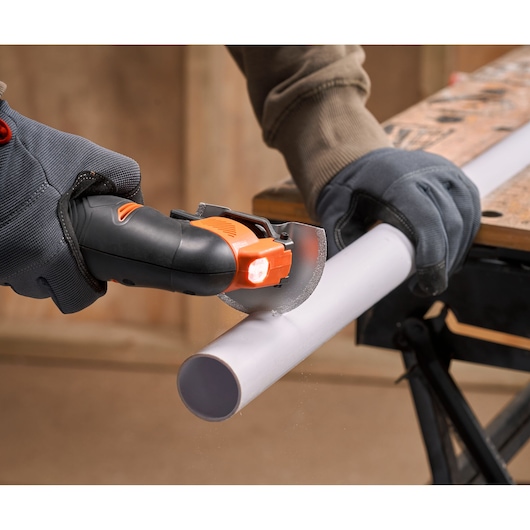 BLACK+DECKER BDCOS18N compacte draadloze zaag zaagt wit kunststof buis, close-up actiebeeld.