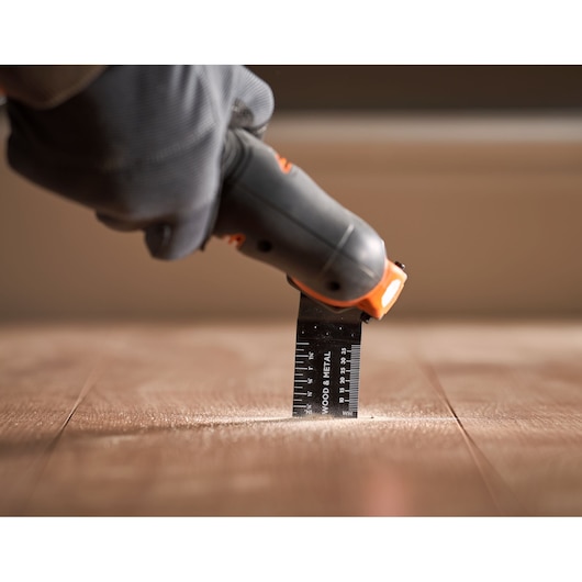 BLACKDECKER BDCOS18N oscillerend gereedschap snijdt houten vloer, close-up fotografie.