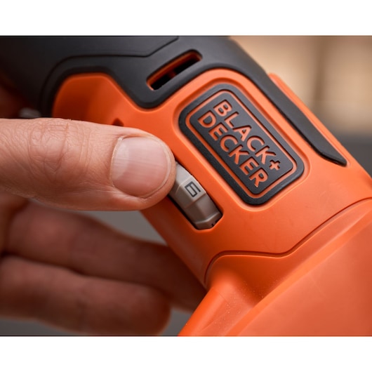 Close-up foto van de oranje BLACK+DECKER BDCOS18N elektrische gereedschap met hand die snelheidsknop verstelt.