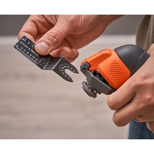 BLACKDECKER BDCOS18N oscillerend gereedschap in hand met hout-metaal zaagblad dat wordt bevestigd, close-up.