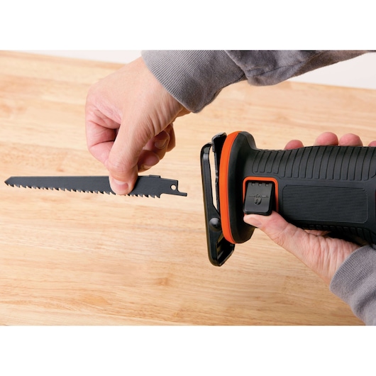 BLACKDECKER BDCR18N reciprozaag close-up, hand verwisselt zaagblad op licht houten oppervlak.