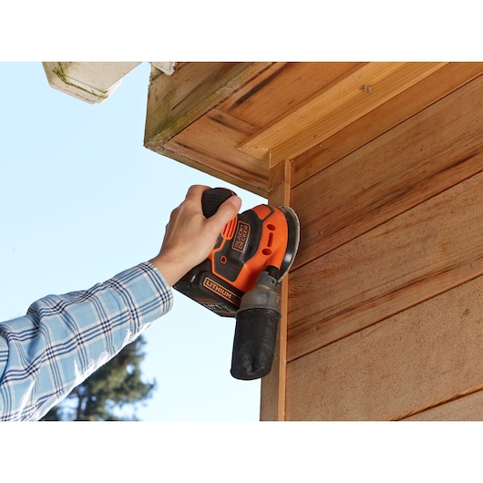 BLACKDECKER BDCROS18N draadloze schuurmachine gebruikt op houten buitenkant, oranje en zwart gereedschap in hand.