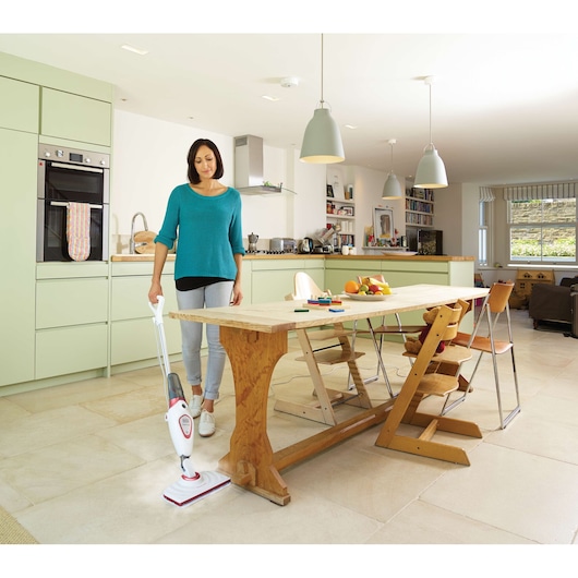 BLACKDECKER BDS1616R balai vapeur utilisé sur carrelage dans une cuisine moderne près d’une table en bois.