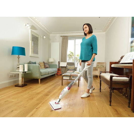BLACKDECKER BDS1616R balai vapeur nettoyant un sol en bois dans le salon, personne utilisant le produit.