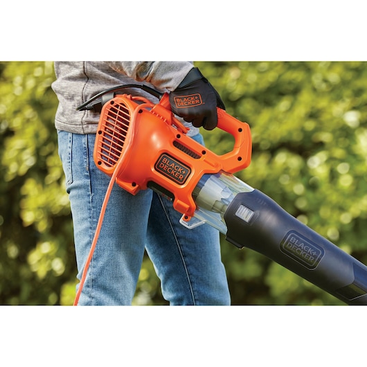 Oranje-zwarte elektrische bladblazer BLACKDECKER BEBL185, vastgehouden door persoon buiten.