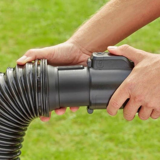 Close-up van BLACK+DECKER BEBLV300 bladblazer flexibele slangverbinding vastgehouden door handen buiten.