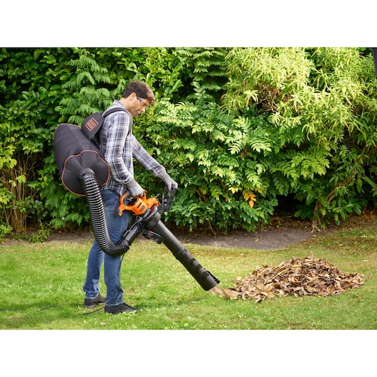 BLACKDECKER BEBLV301 bladblazer met rugzak verzamelt bladeren buiten.