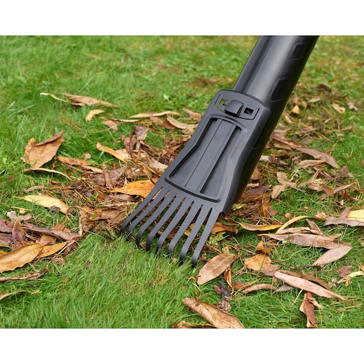 BLACKDECKER BEBLV301 bladblazerbuis met harkopzetstuk op gras met droge bladeren, close-up.