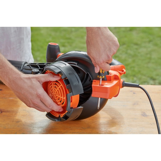 BLACKDECKER BEBLV301 bladblazer close-up, persoon zet oranje kap vast met schroevendraaier.