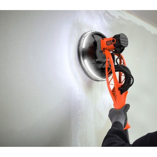 BLACKDECKER BEDW700A8S gipsmuur schuurmachine met LED-ring, gebruikt op een muur, close-uphoek.