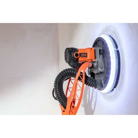 BLACK+DECKER elektrische wandschuurmachine met LED-licht schuurt een witte muur.