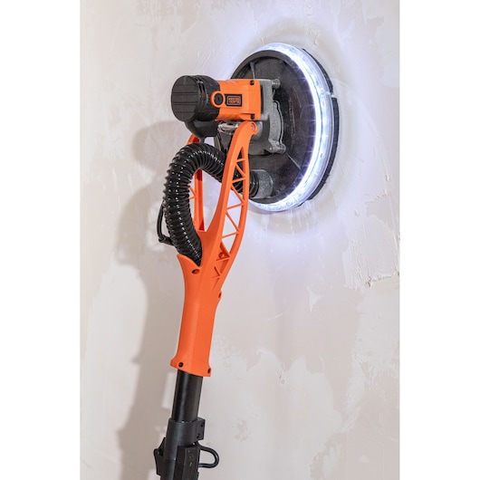 BLACK+DECKER muurschuurmachine met ledlamp schuurt een wandoppervlak.