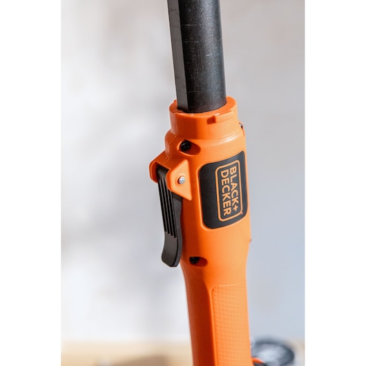 Close-up van BLACK+DECKER oranje handvat met zwarte label en hendel, onderdeel van een powertool.