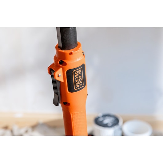 Dichtbij van een oranje BLACK+DECKER handgreep met trekker en logo, onderdeel van een elektrisch gereedschap.