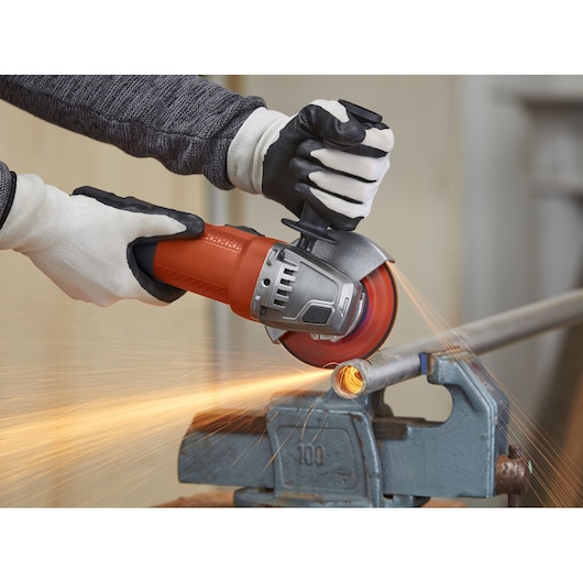 Foto van BLACKDECKER BEG110 haakse slijper die een metalen pijp doorsnijdt met vonken.