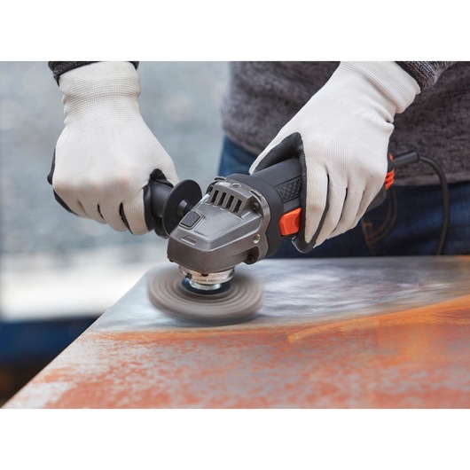 BLACKDECKER BEG220K haakse slijper in gebruik op metalen oppervlak, close-up met handschoenen.