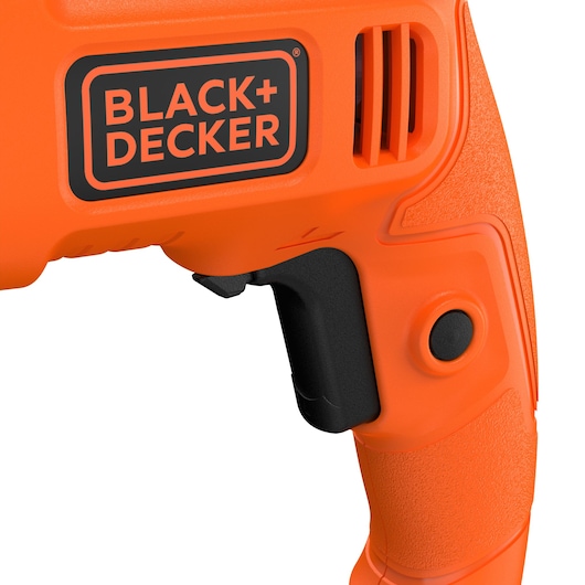 Close-up van het handvat en de trekker van een oranje BLACK+DECKER elektrisch gereedschap, met het merklogo en een getextureerde grip.