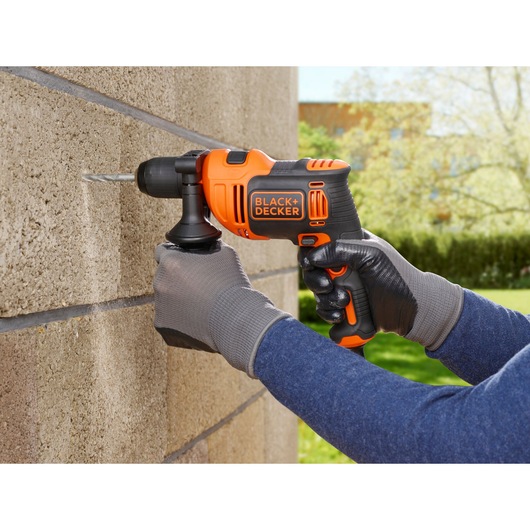BLACK+DECKER BEH550 perceuse filaire en utilisation perçant un mur en béton à l'extérieur.