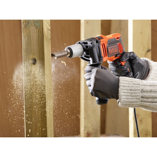 BLACK+DECKER BEH850K perceuse à percussion utilisée pour percer du bois, poussière volante, vue rapprochée.