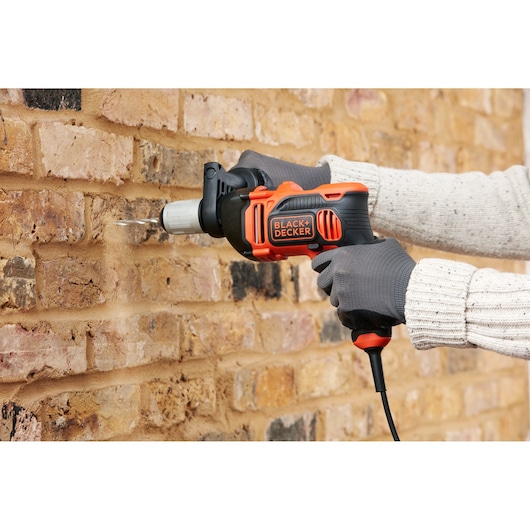 BLACKDECKER BEH850K perceuse à percussion filaire utilisée pour percer un mur en briques, vue rapprochée.