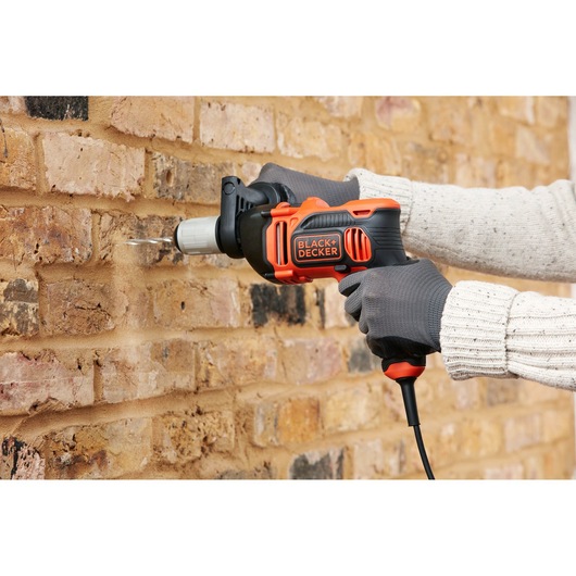 BLACKDECKER BEH850 perceuse à percussion filaire utilisée sur mur en briques, photographie produit, angle latéral