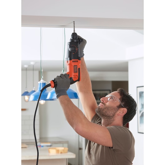 Photographie de la BLACKDECKER BEHS01K perceuse à percussion filaire utilisée pour perçage en hauteur en intérieur.
