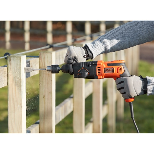 BLACKDECKER BEHS01 perceuse à percussion filaire utilisée pour percer du bois en extérieur avec des gants.