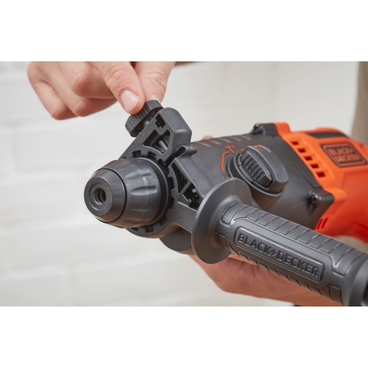Photo d'une perceuse à percussion BLACK+DECKER BEHS01 en gros plan, poignée avant réglable et cadran latéral, main réglant le réglage.