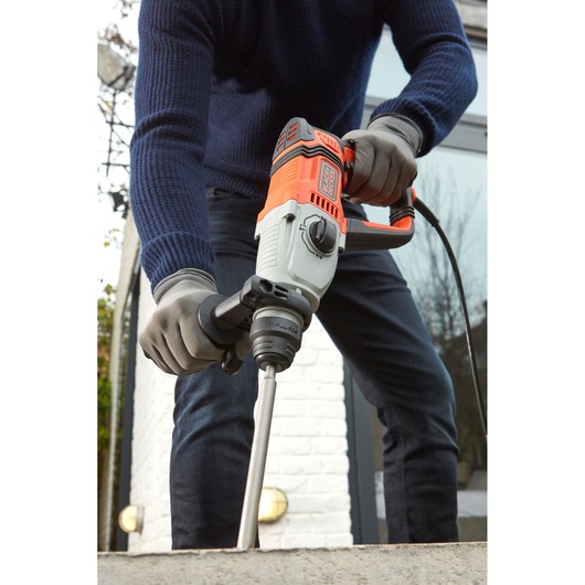 BLACKDECKER BEHS02K marteau perforateur en action, design orange et gris, tenu par une personne avec des gants.
