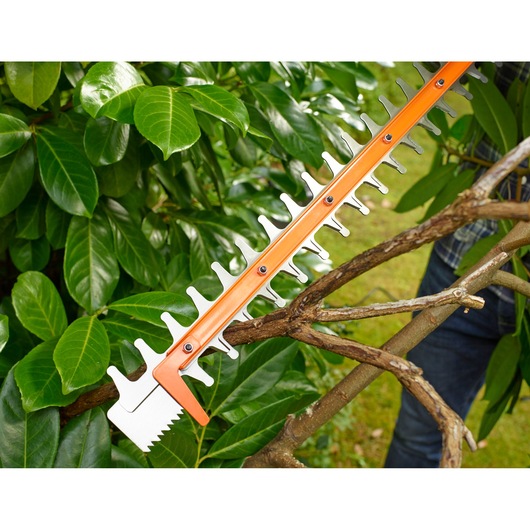 BLACKDECKER BEHTS401 heggenschaarmes snijdt takken in tuinomgeving.
