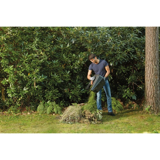 Bac à herbe de tondeuse BLACKDECKER BEMW351GL2 vidé par un homme sur un tas de compost au jardin.