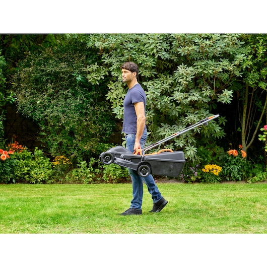 Photo de BLACKDECKER BEMW351 tondeuse à gazon transportée sur l'herbe dans un jardin.