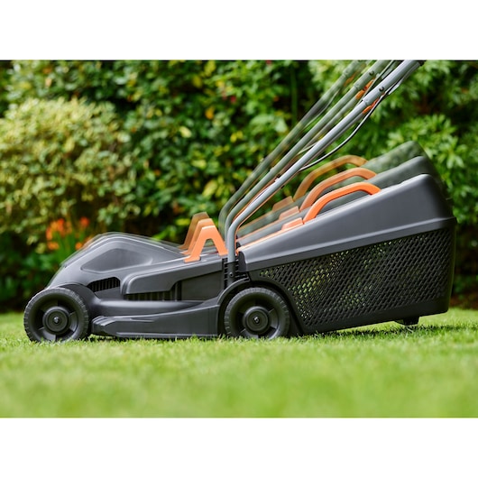 BLACKDECKER BEMW351 tondeuse à gazon avec poignée réglable sur l’herbe, vue latérale, fond de jardin.