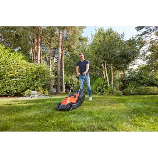 BLACKDECKER BEMW451 tondeuse électrique utilisée sur une pelouse dans un jardin.