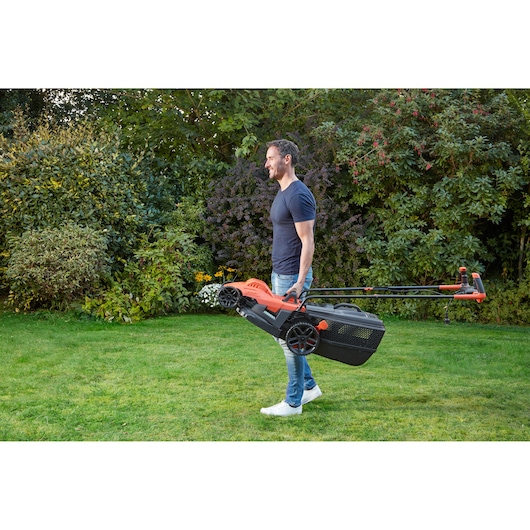 BLACKDECKER BEMW461BH tondeuse à gazon avec poignée, portée par une personne dans un jardin.