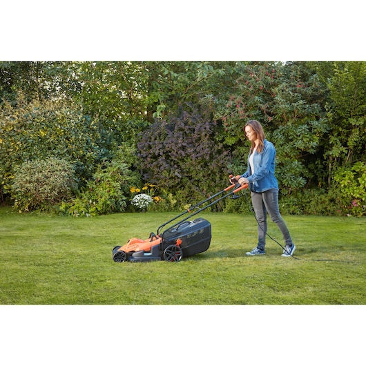 BLACKDECKER BEMW481BGL2 grasmaaier in gebruik buiten op gras, oranje en zwart design.