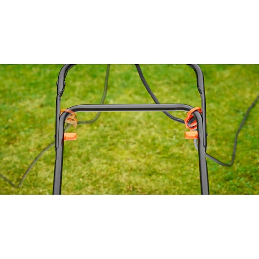 BLACKDECKER BEMW481BGL2 grasmaaier handgreep frame met oranje kabelhouders, gras op achtergrond
