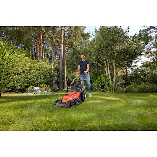 BLACKDECKER BEMW481BGL2 grasmaaier in gebruik op gras, oranje en zwart ontwerp, tuinomgeving buiten.
