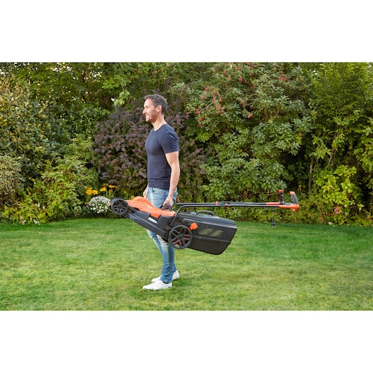BLACKDECKER BEMW481BH tondeuse avec poignée portée par une personne à l'extérieur sur l'herbe.