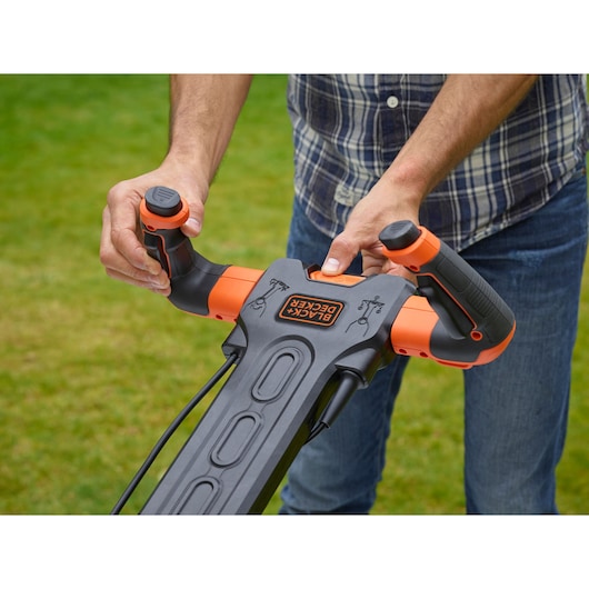 Foto van BLACKDECKER BEMW481ES grasmaaierhandvat met ergonomische oranje en zwarte bediening, buiten in gebruik.