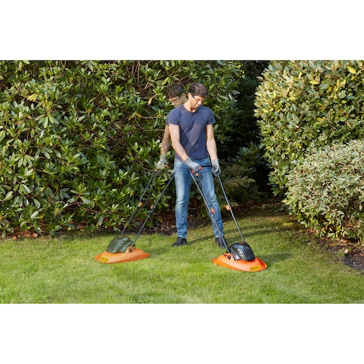BLACKDECKER BEMWH551 tondeuses sur gazon, homme derrière les deux, décor de jardin.
