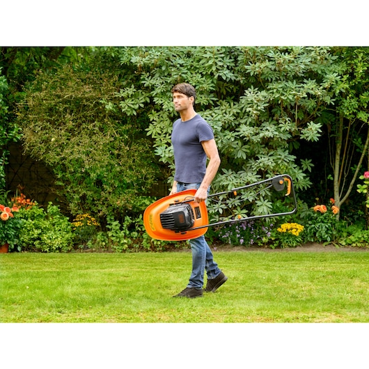 Homme portant la tondeuse à gazon orange BLACKDECKER BEMWH551 dans le jardin.