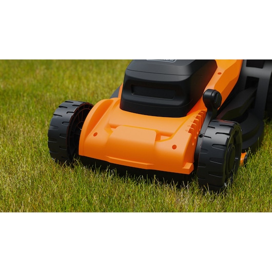 BLACKDECKER BEMWP340-QS tondeuse vue rapprochée sur l’herbe, avant orange et noir avec grandes roues.