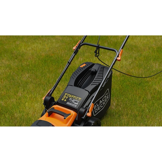 BLACK+DECKER BEMWP340-QS tondeuse électrique gros plan sur l’herbe, avec poignée et étiquettes de sécurité.