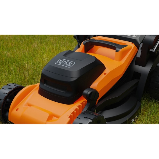 Gros plan sur la tondeuse orange et noire BLACK+DECKER BEMWP340-QS sur l’herbe verte.