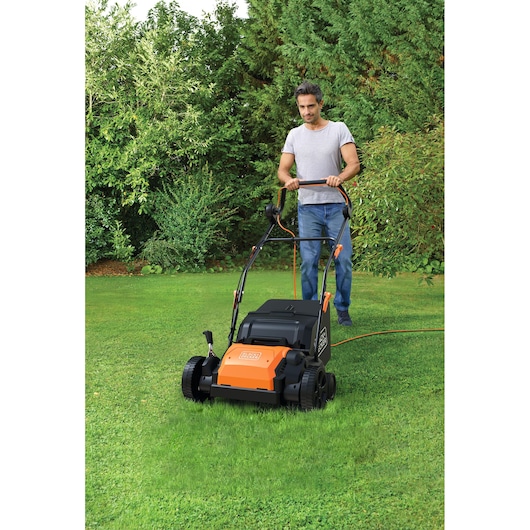 Scarificateur de pelouse BLACKDECKER BEOEP320-QS orange et noir utilisé sur la pelouse verte.