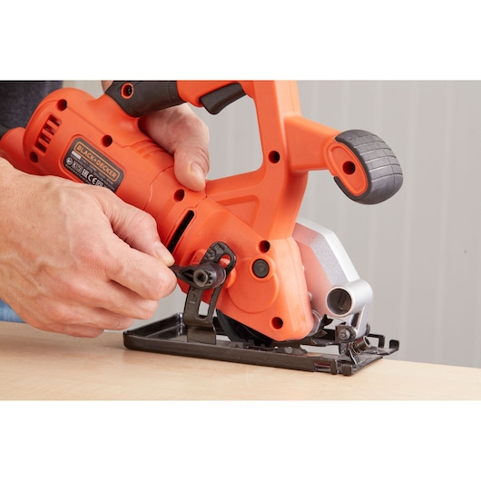 Foto van BLACK+DECKER BES510 compacte cirkelzaag die wordt afgesteld op een houten oppervlak, close-up.