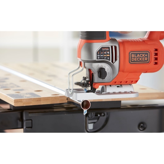 Foto van BLACK+DECKER BES610K decoupeerzaag die een metalen buis zaagt op een werkbank, close-up.