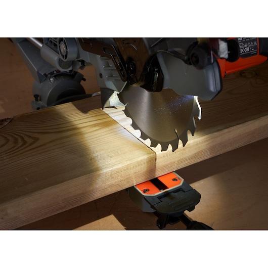 BLACKDECKER BES701 afkortzaagblad zaagt een lichtgekleurde houten plank, zijaanzicht, close-up.