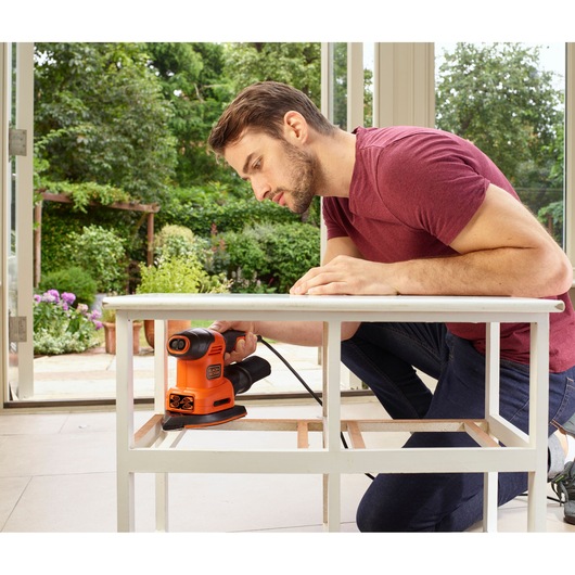 BLACKDECKER BEW200K schuurmachine in gebruik op witte tafel, binnenshuis werkplaats, productfoto.